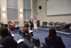 Na środku auli stoja dwie Panie i przemawiają przed uczestnikami